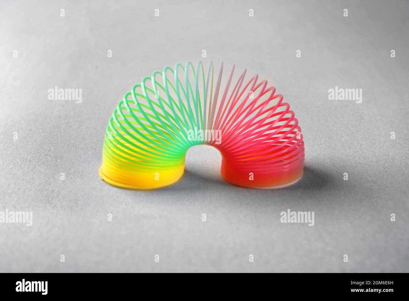 Rainbow slinky on grey background Stock Photo - Alamy