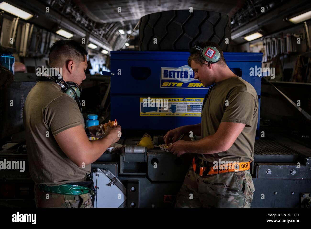 U.S. Air Force Tech. Sgt. Facundo Santamina, left, and Senior Airman James Reed, both 62nd Aircraft Maintenance Squadron crew chiefs, break to eat a quick meal before loading more supplies on a C-17 Globemaster III from McChord Air Force Base, Washington, Aug. 25, 2021, on the flight line at Travis AFB, California. The McChord C-17 stopped while en route to an undisclosed location in support of Operation Allies Refuge to pick up Airmen and equipment from the 860th and 660th AMXS. The two maintenance squadrons maintain the C-17 and KC-10 Extender, respectively. The U.S. Air Force, in support of Stock Photo