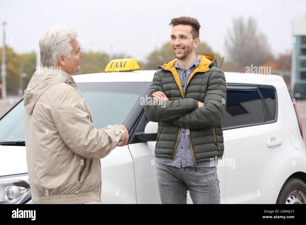 Young trainee and senior driver talking near taxi car Stock Photo Alamy