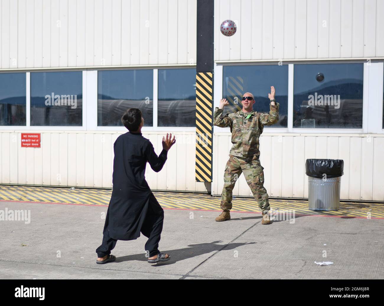 An Airman plays ball with an evacuee at Ramstein Air Base, Germany, Sept. 8, 2021. RAB welcomed approximately 16,800 evacuees making it one of the largest, most complex humanitarian operations in history. (U.S. Air Force photo by Tech. Sgt. Crystal L. Charriere) Stock Photo