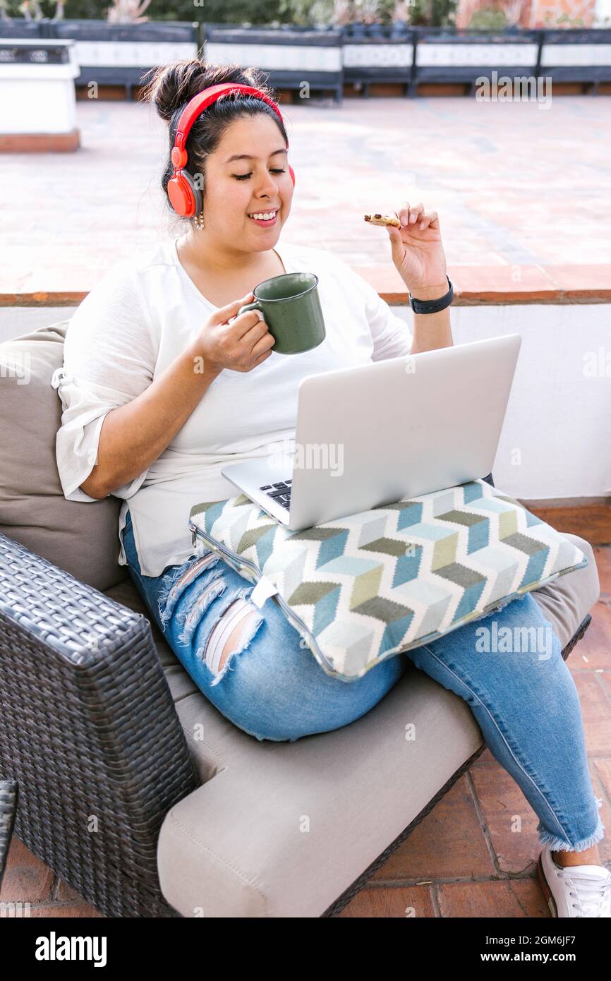 Young mexican female with headphones listening to music on computer ...
