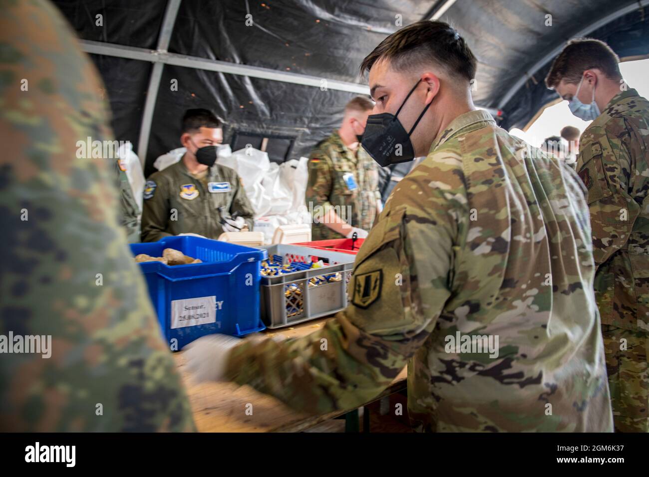 Service members from the U.S. Army and Air Force work shoulder to shoulder with soldiers from the German Bundeswehr to prepare meals for the Afghanistan evacuees. Ramstein Air Base is a transit center that provides a safe place for the evacuees to complete their paperwork while security and background checks are conducted before they continue on to their final destination. (U.S. Army photo by Staff Sgt. Thomas Mort) Stock Photo