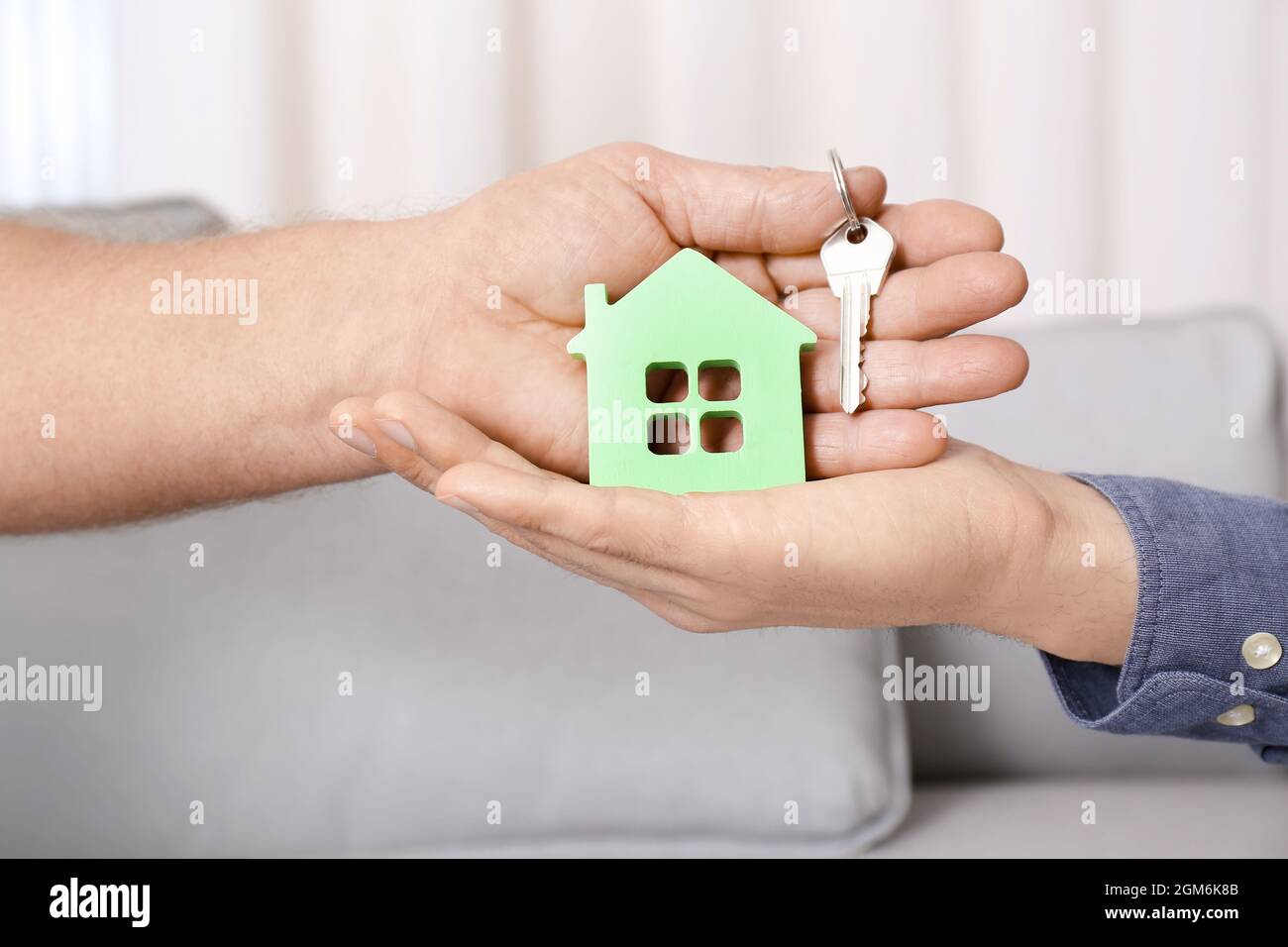 Real estate agent with senior man holding house model and key indoors ...