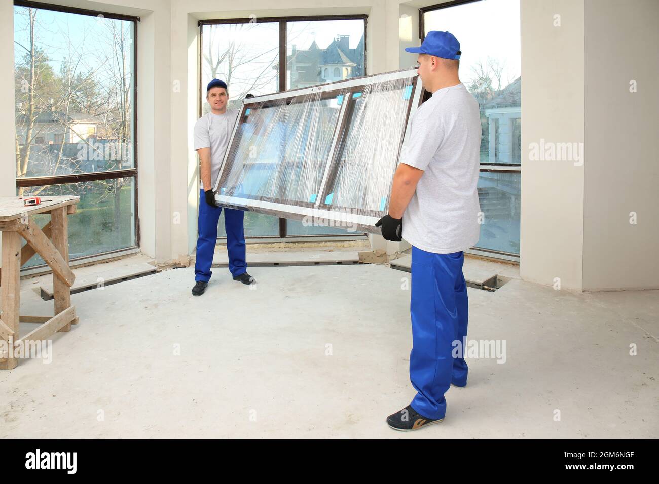 Construction workers carrying window glass indoors Stock Photo - Alamy