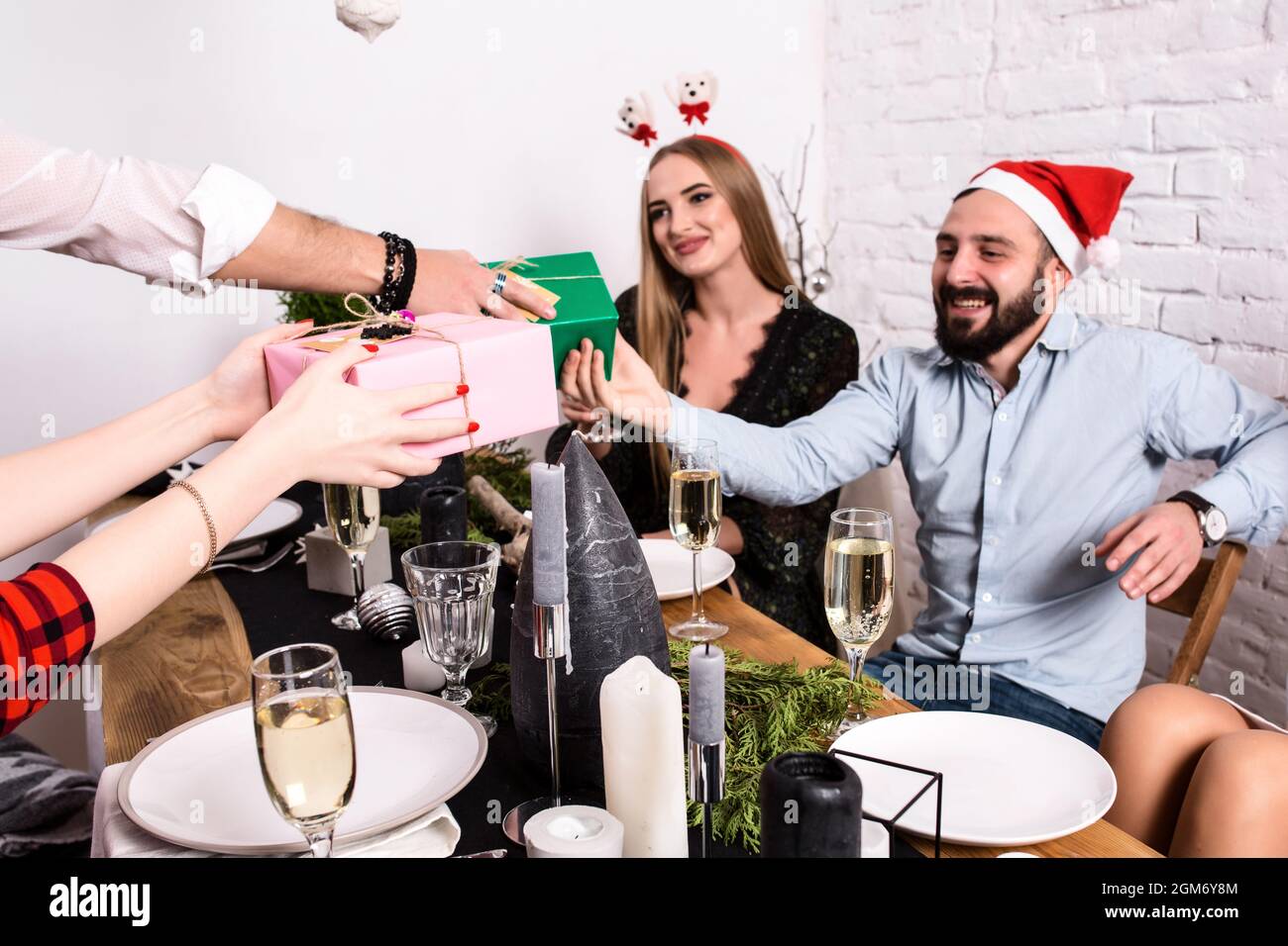 Picture showing group of friends celebrating Christmas at home and giving presents to each other Stock Photo