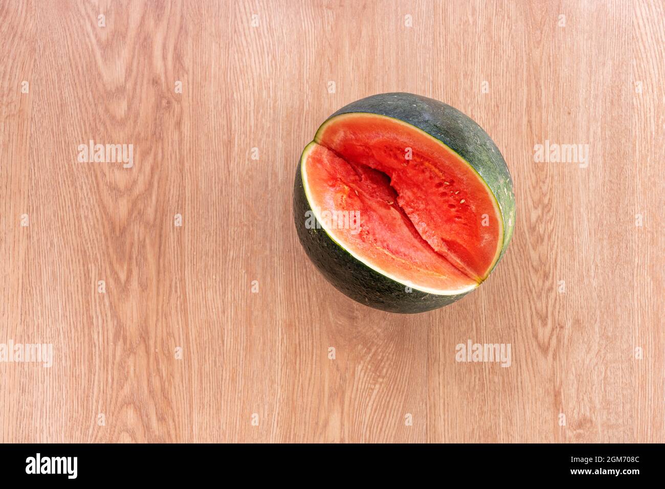 Seedless watermelon which has been cut a generous piece to cool off at ease on an oak floor background Stock Photo