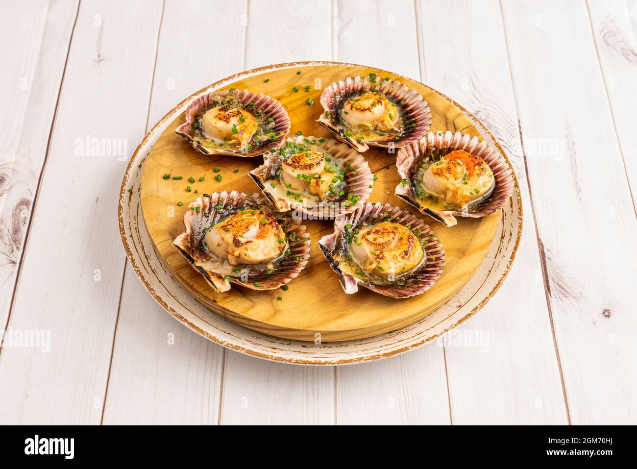 Recipe of delicious Galician scallops caught on the coast of death served on a traditional wooden plate Stock Photo