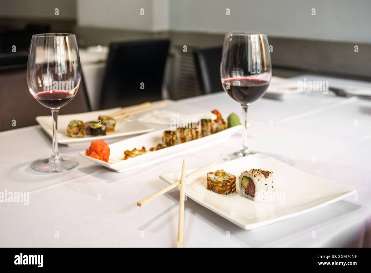 Assorted uramaki dishes with wine glasses on restaurant table with white tablecloths Stock Photo