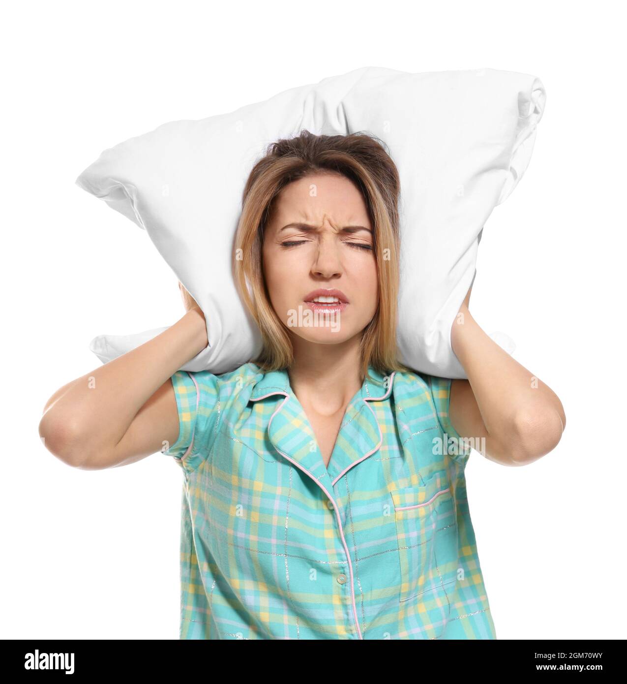 Young woman covering her ears with pillow on white background Stock