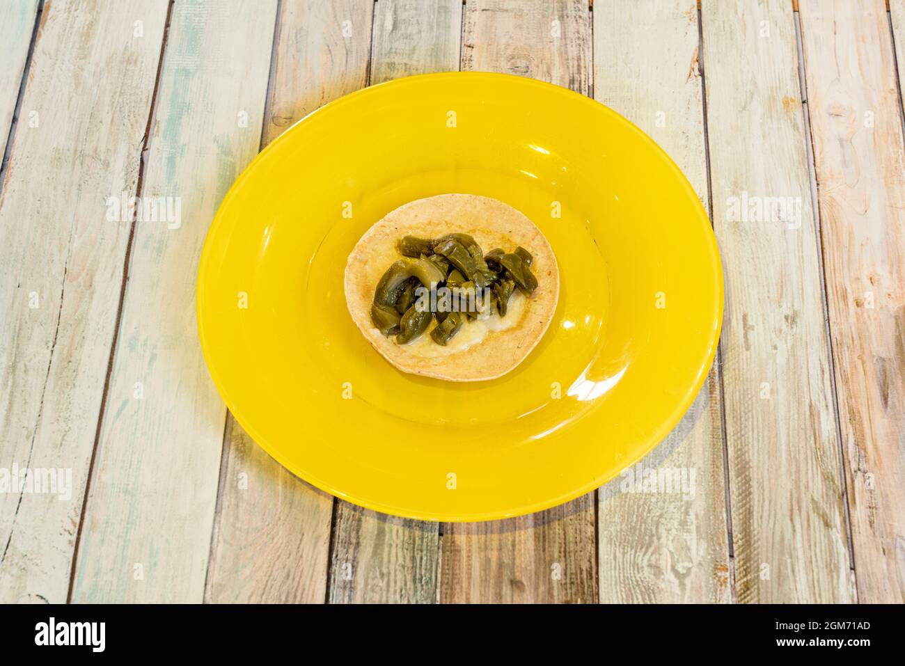 Simple taco of nopales with melted cheese and corn tortilla on a yellow plate. Stock Photo