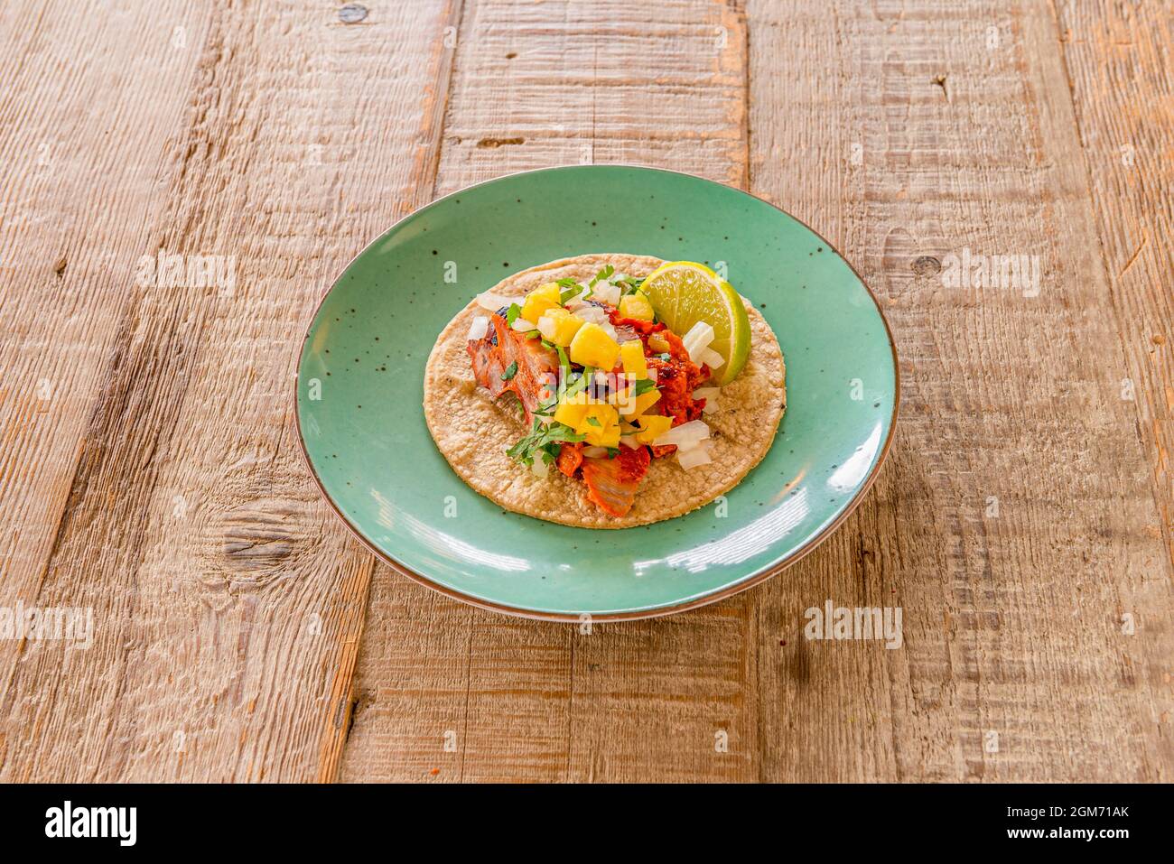 Typical mexican pastor taco with lime and corn tortilla on green plate Stock Photo