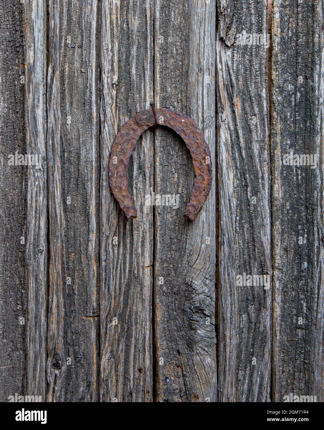 very old horse horseshoe symbol of good luck hanging on a rusty nail on a wooden door Stock Photo