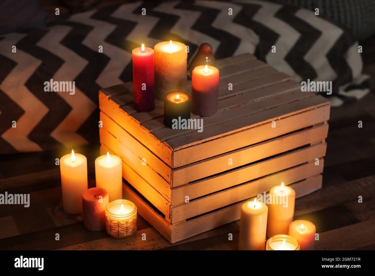 Burning candles and wooden crate indoors Stock Photo - Alamy