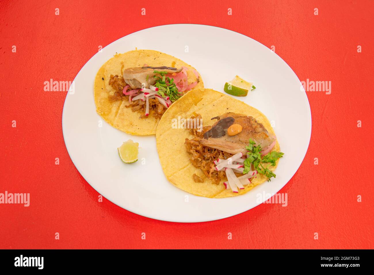 Assorted Mexican tacos with meat, lime and radishes on white plate and red background Stock Photo