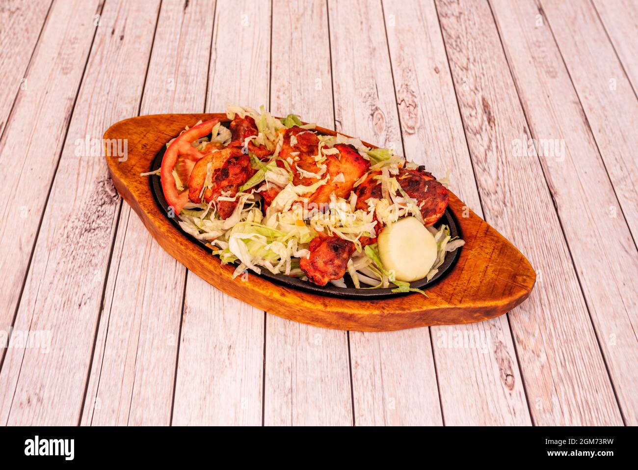 Grilled tandoori chicken tray with lettuce and tomato garnish served in