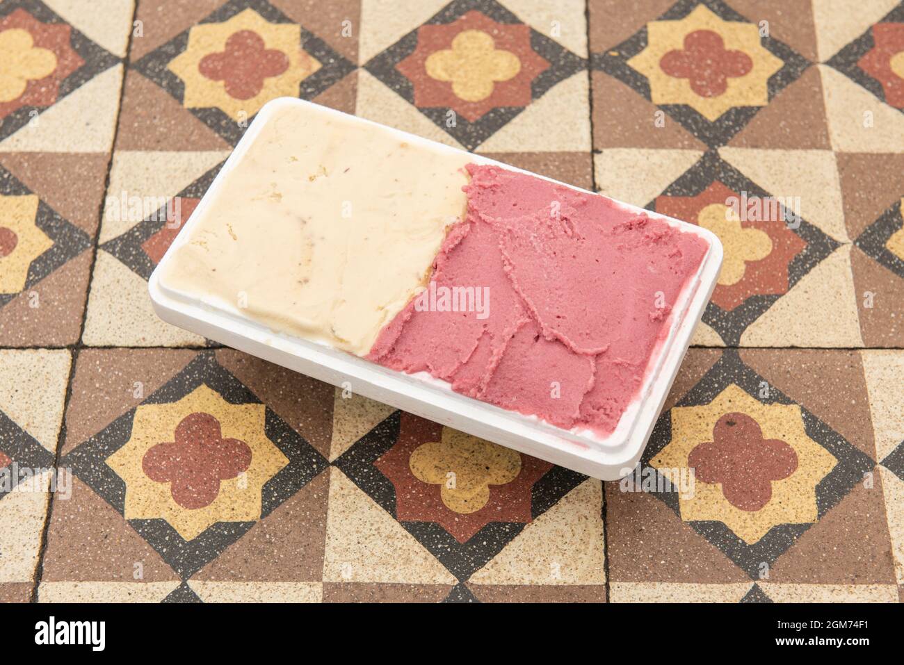 Half-liter tub of ice cream with two flavors in a home delivery container on hydraulic tiles Stock Photo