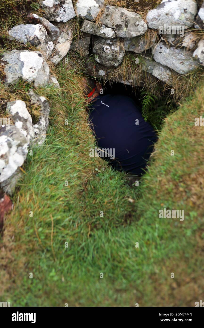 Souterrain on the Isle of Canna being explored by a man wearing a head torch Stock Photo