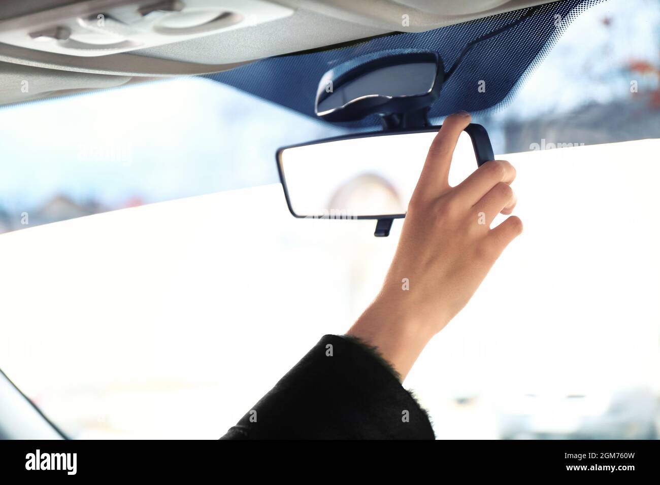 Woman adjusting rear view mirror in car Stock Photo Alamy