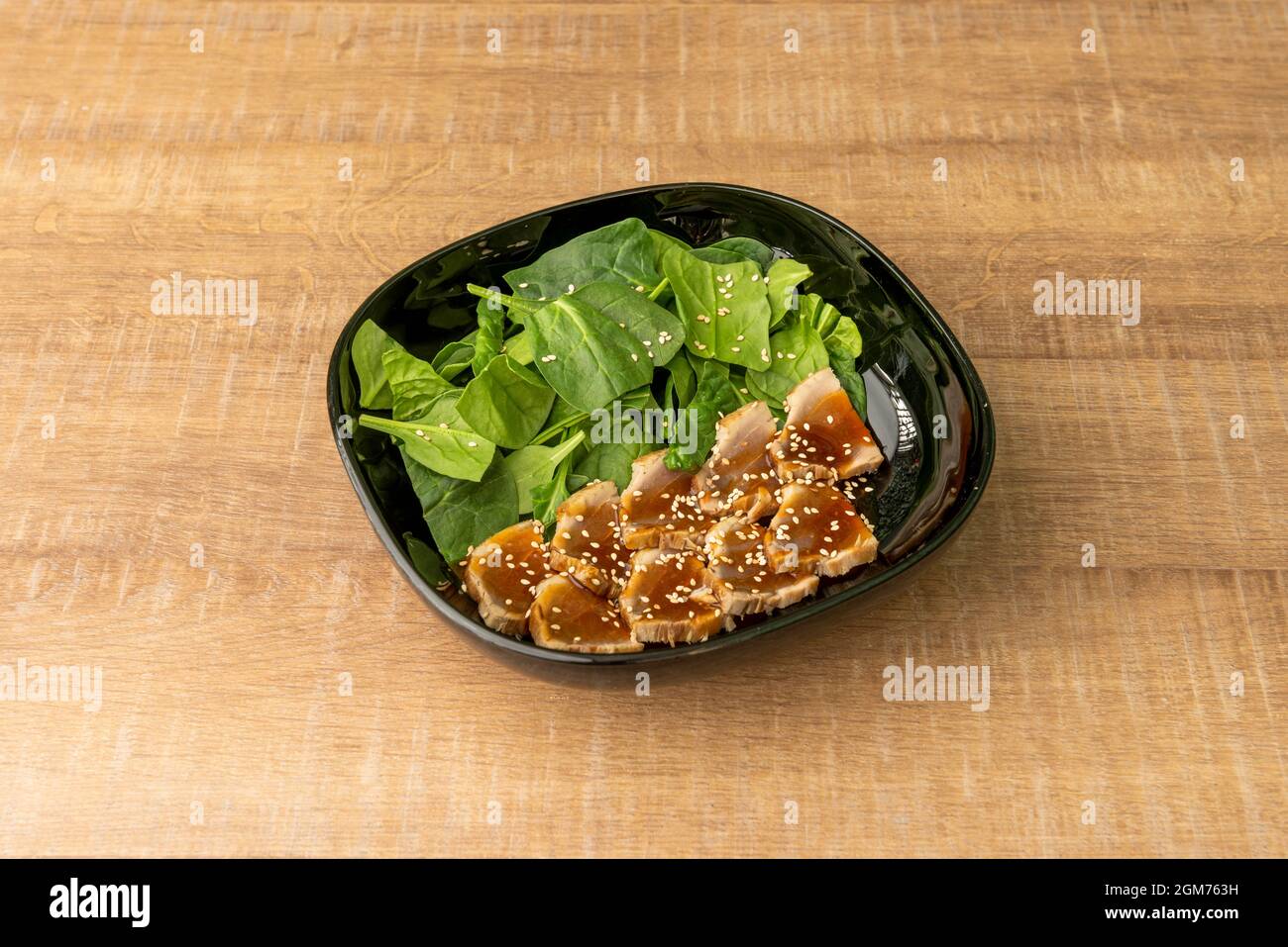 slices of red tuna tataki with sesame seeds and spinach salad inside a