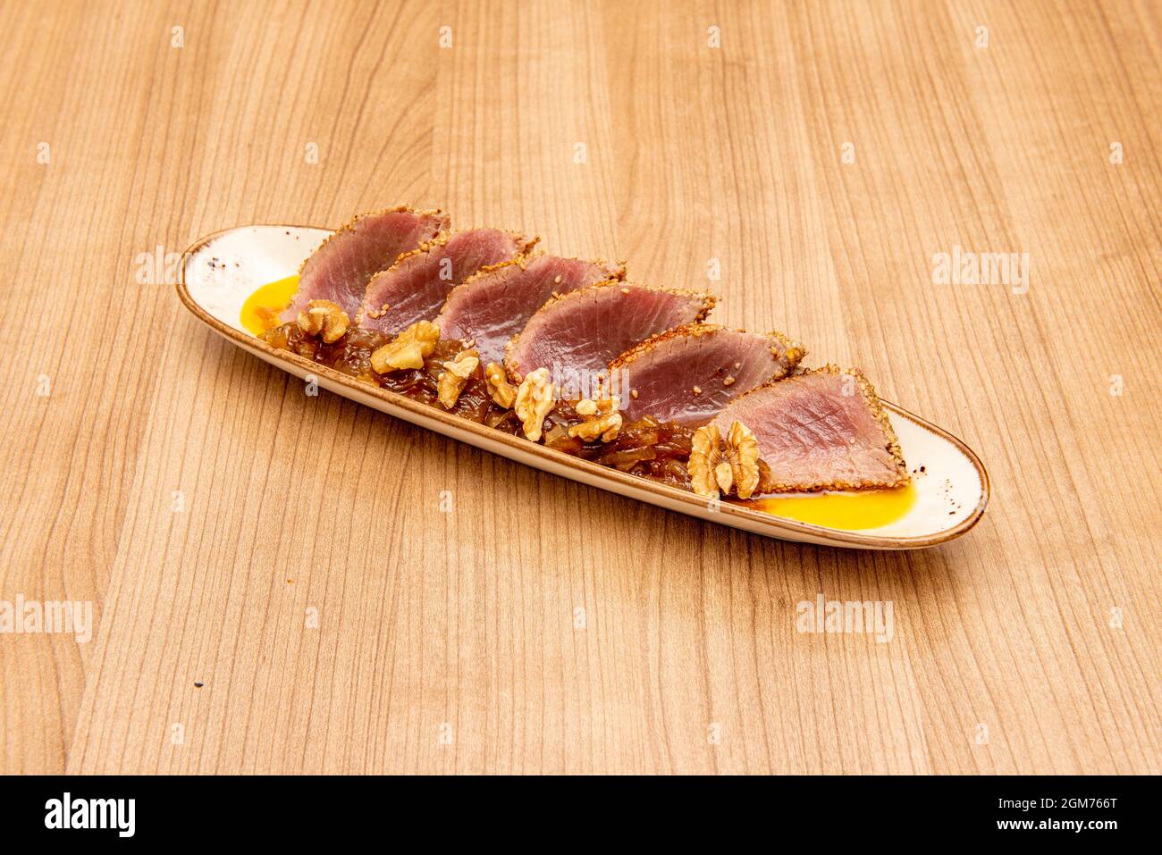 red tuna tataki marked on the edges with sweet sauce and pieces of walnuts Stock Photo