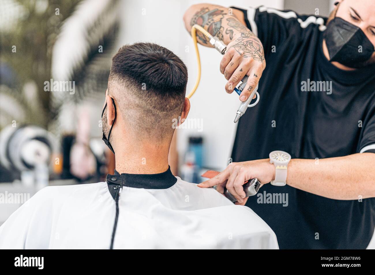 Barber removing excess hair from a customer with an air blower in a
