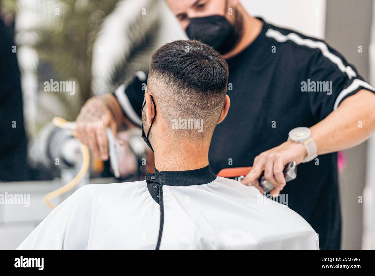 Selective focus on the shaved nape of a man with mask in a barbershop Stock Photo