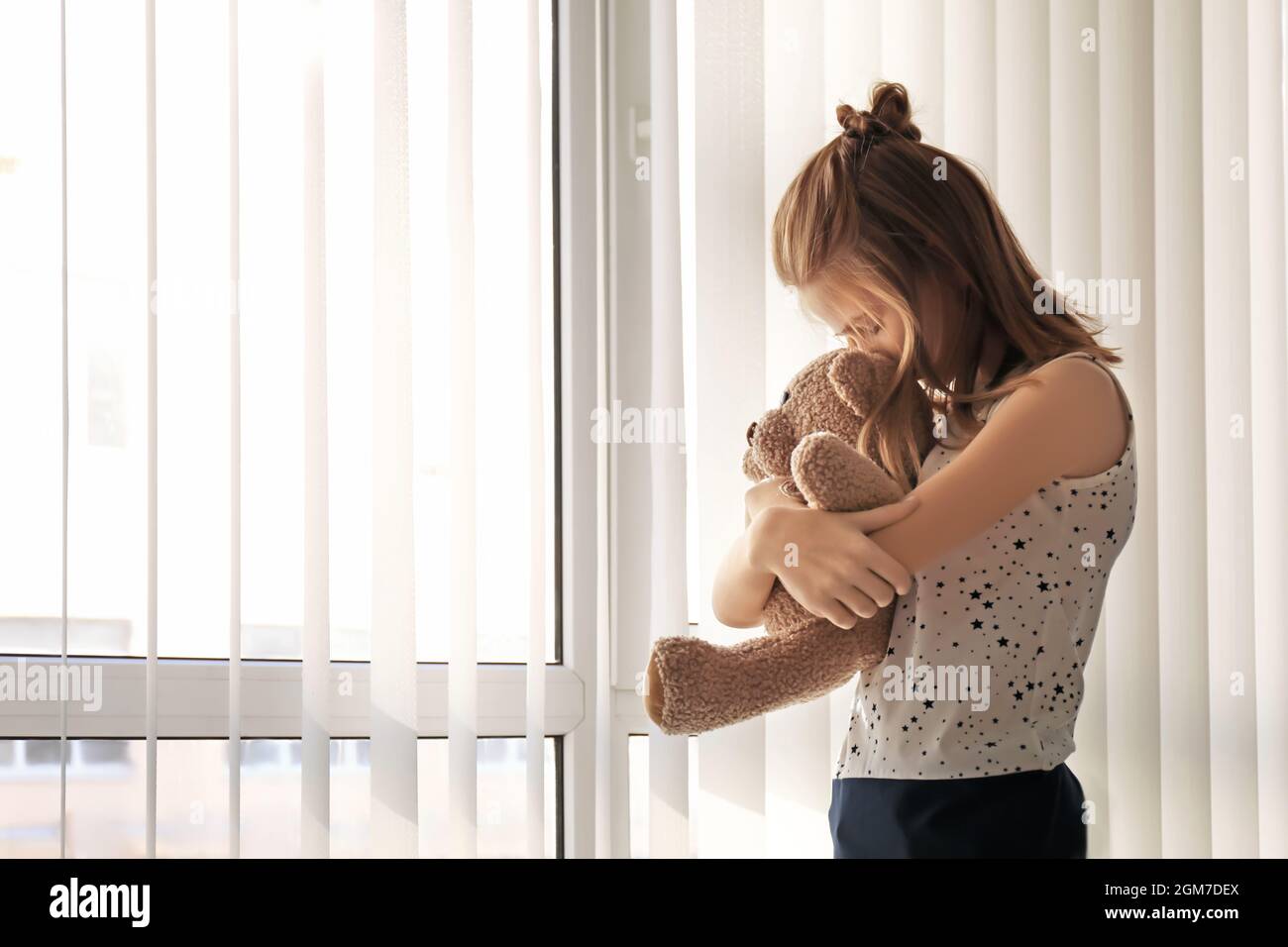 Little girl with teddy bear near window. Autism concept Stock Photo - Alamy