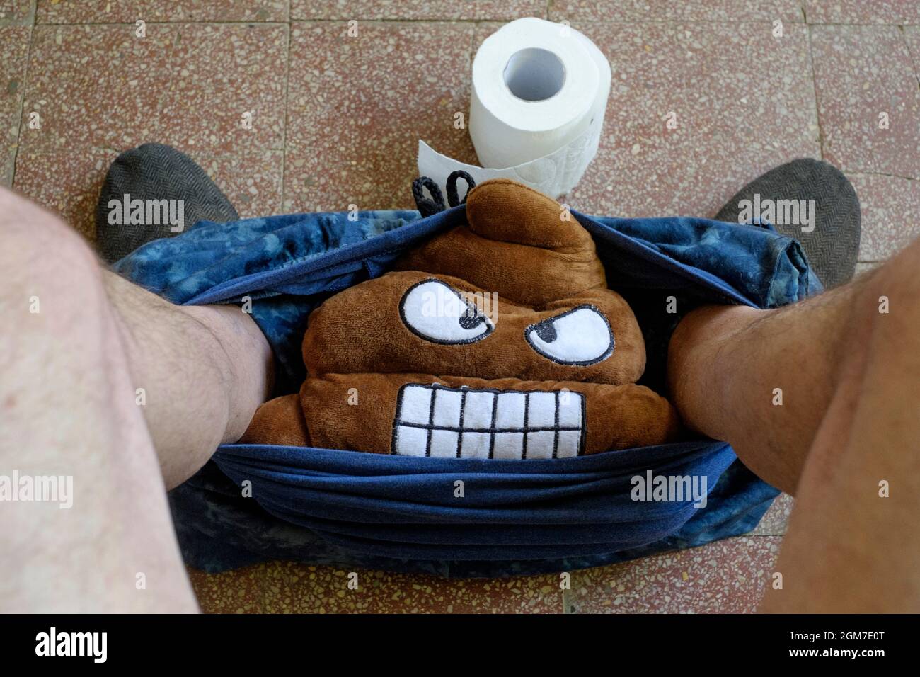 man with trousers around ankles with toilet roll on floor and soft toy
