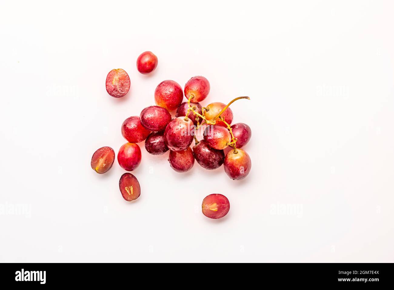 Small bunch of ripe dessert grapes on white background, some split in half Stock Photo