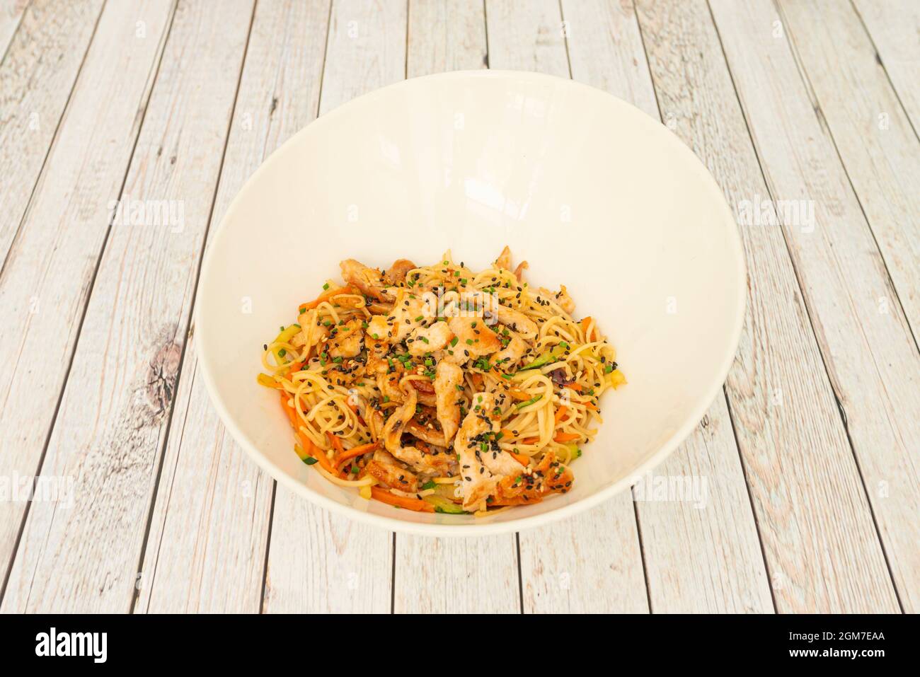 noodles with chicken, vegetables and seeds sauteed with yakisoba sauce in a white bowl Stock Photo