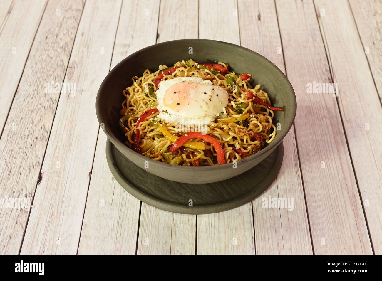 Asian noodle pasta with sesame, sautéed fried peppers and fried egg on top Stock Photo