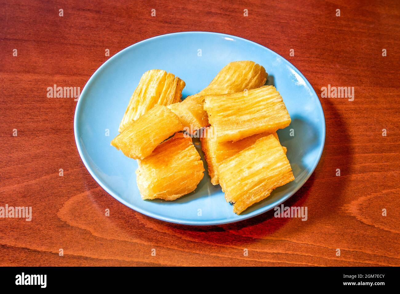 Pieces of tasty Caribbean cassava cooked and then fried in olive oil on a blue plate Stock Photo