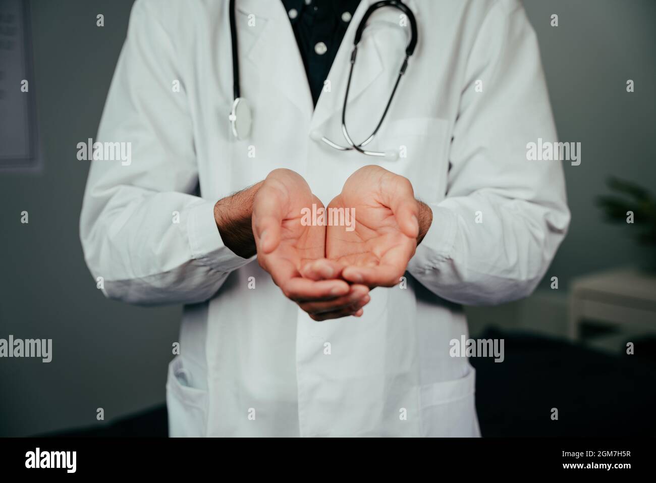 caucasian male doctor standing in office with hands open Stock Photo