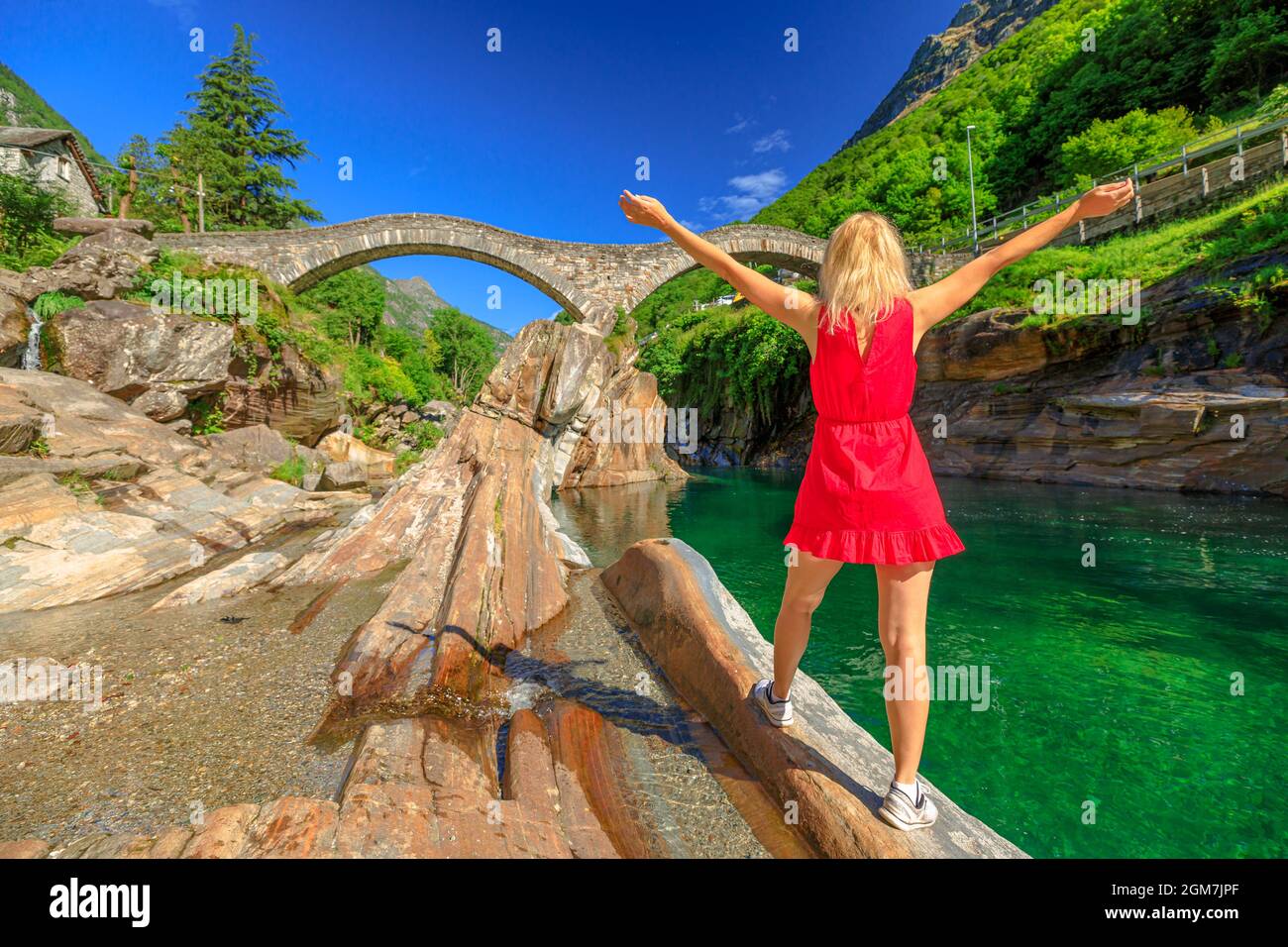Woman by Roman stone bridge: Ponte dei Salti over Verzasca River. Verzasca valley by Lavertezzo town. Famous landmark for riverside leisure and high Stock Photo