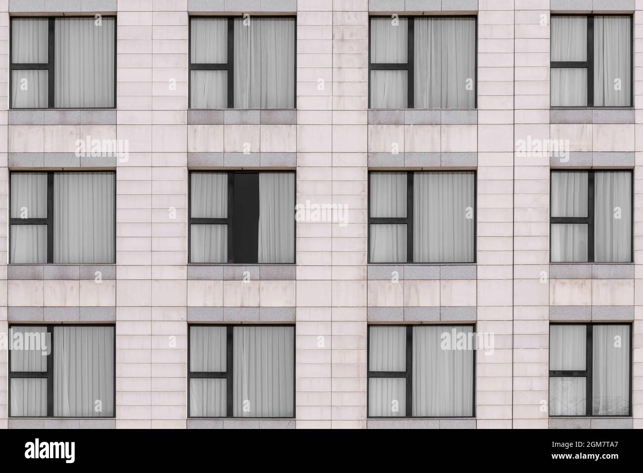 White marble granite facade and multiple windows closed with black metal frames Stock Photo