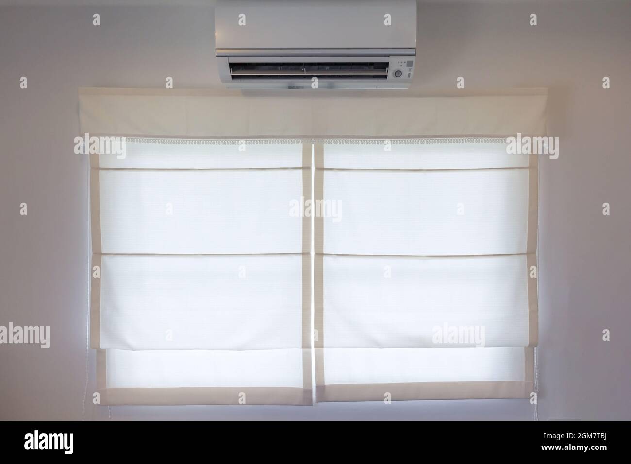 white air conditioner hanging on the wall above the window and white