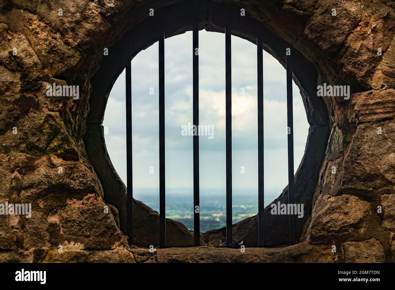 view through barred stone circular window at Mow Cop hill top folly staffordshire Stock Photo