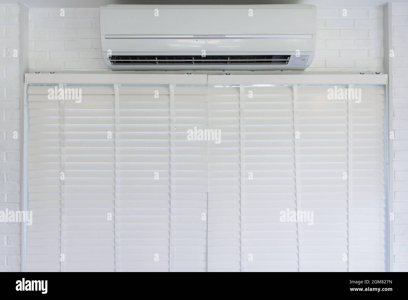 white air conditioner hanging on the wall above the window and white