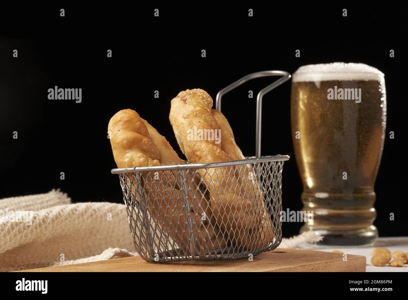Empanadas inside deep fryer with glass of beer in the background Stock