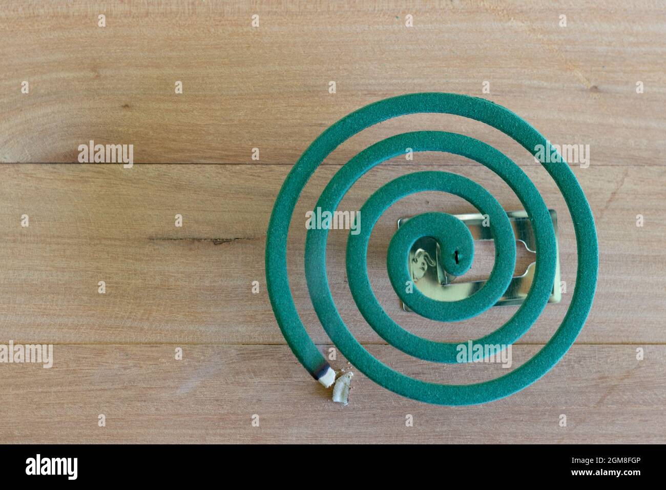 Green mosquito repellent burning and white smoke on wooden table with green blur light Stock