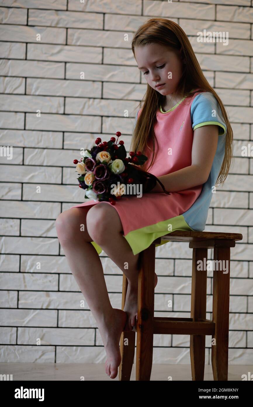 little girl is sitting on a chair and posing on the camera Stock Photo ...