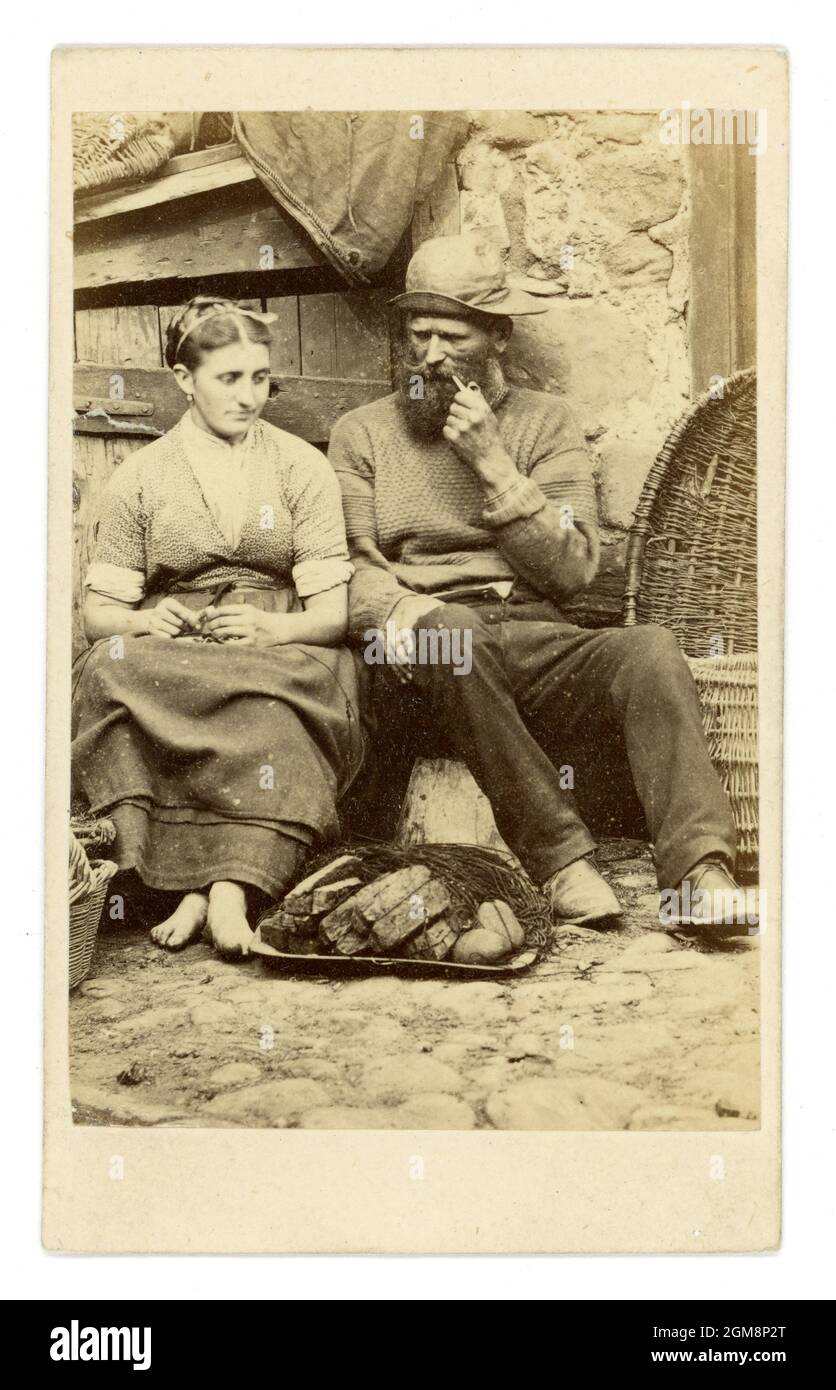 Original Victorian CDV (Carte de Visite) greetings card, made for the holiday trade at the time. Depicts a fisherman, smoking a pipe, wearing a traditional fisherman's jumper, with his wife who is barefoot at Cullercoats, Northumberland, Northern England, U.K. Circa 1860. Stock Photo