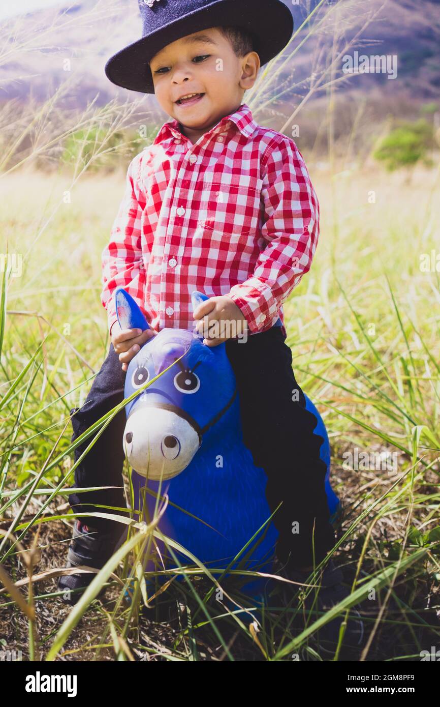 White boy dressed as a cowboy, playing in the woods with his toy horse.  Child portrait for children's day, children's fashion, country fashion  Stock Photo - Alamy