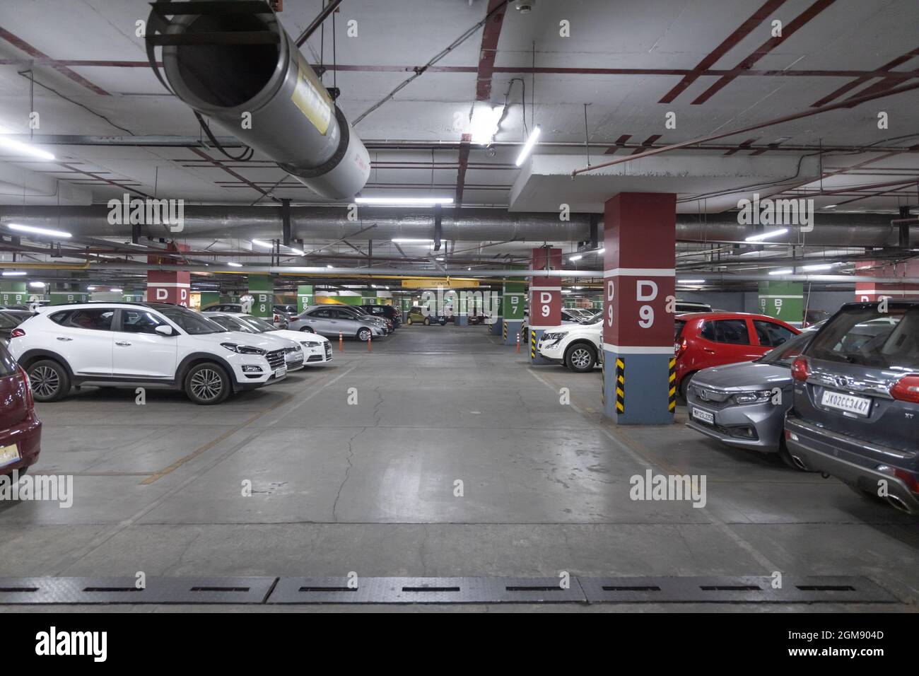 Many cars parked in a row in a basement parking in a shopping mall at