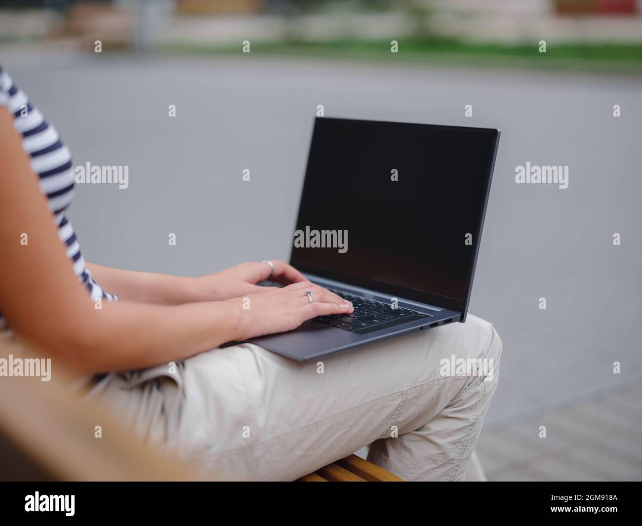 Young asian female student working at laptop sit down on bench outside ...
