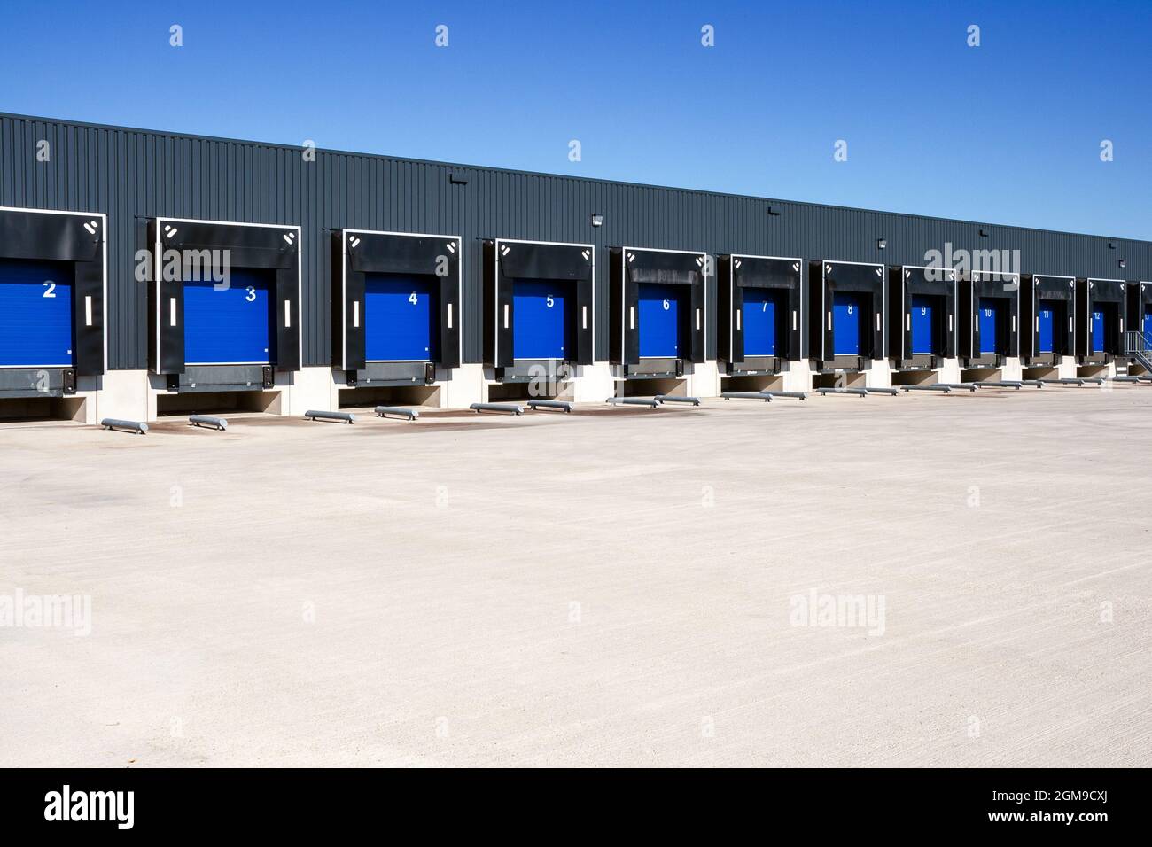 Row of loading docks with shutter doors at an industrial warehouse. Stock Photo