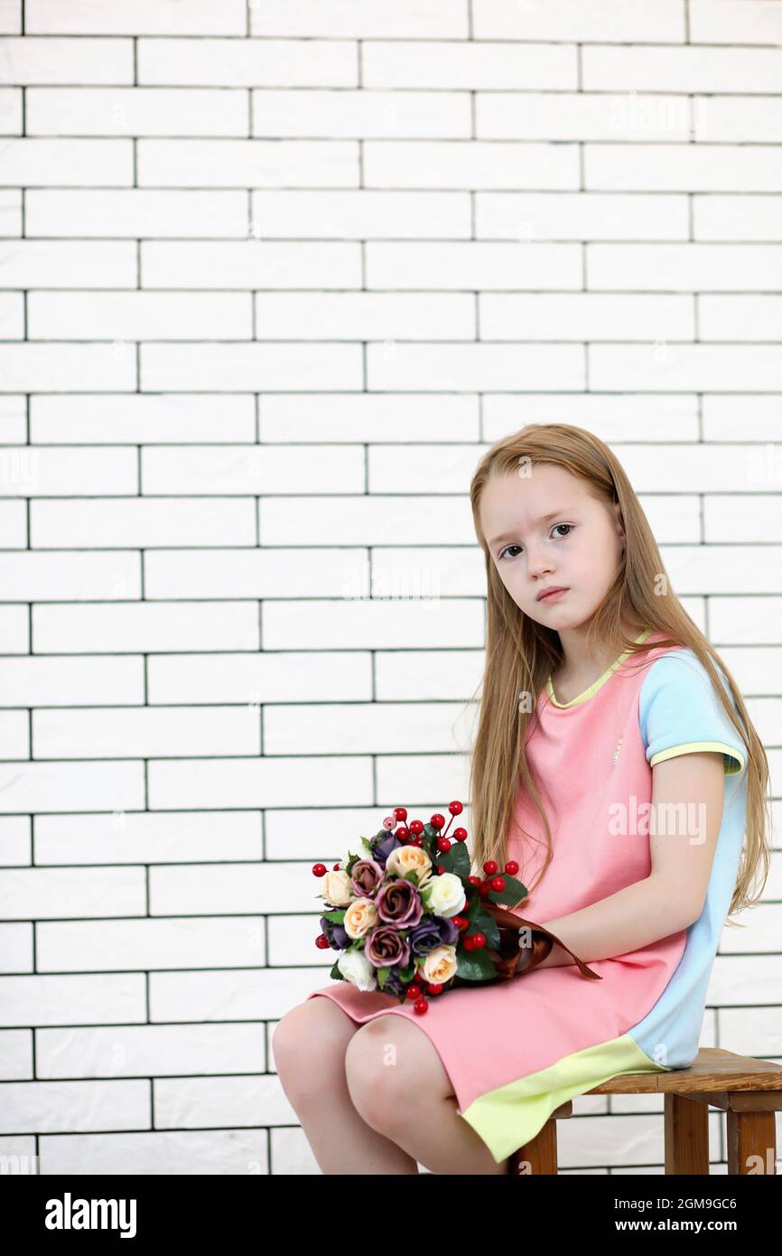 little girl is sitting on a chair and posing on the camera Stock Photo ...