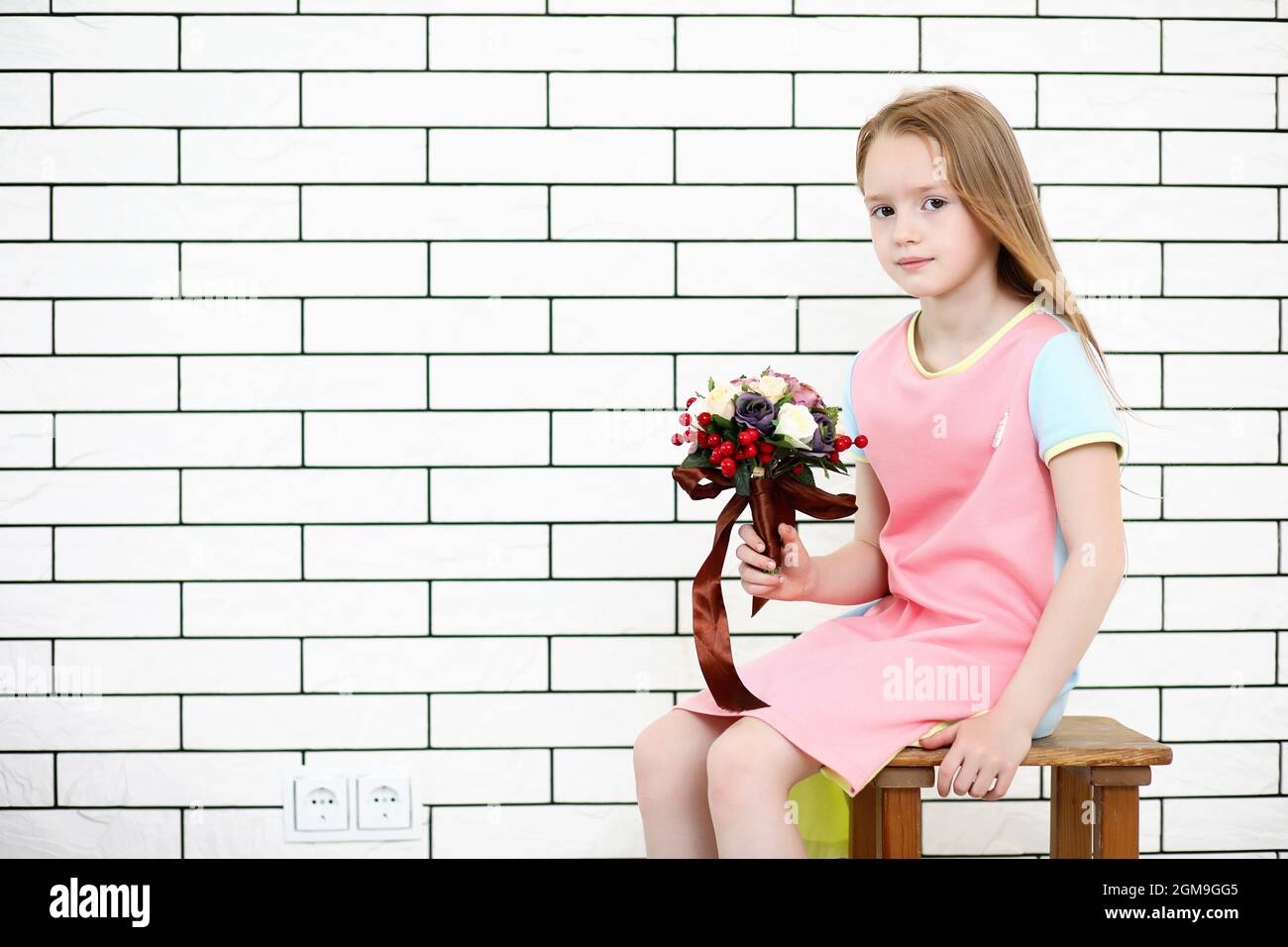 little girl is sitting on a chair and posing on the camera Stock Photo ...