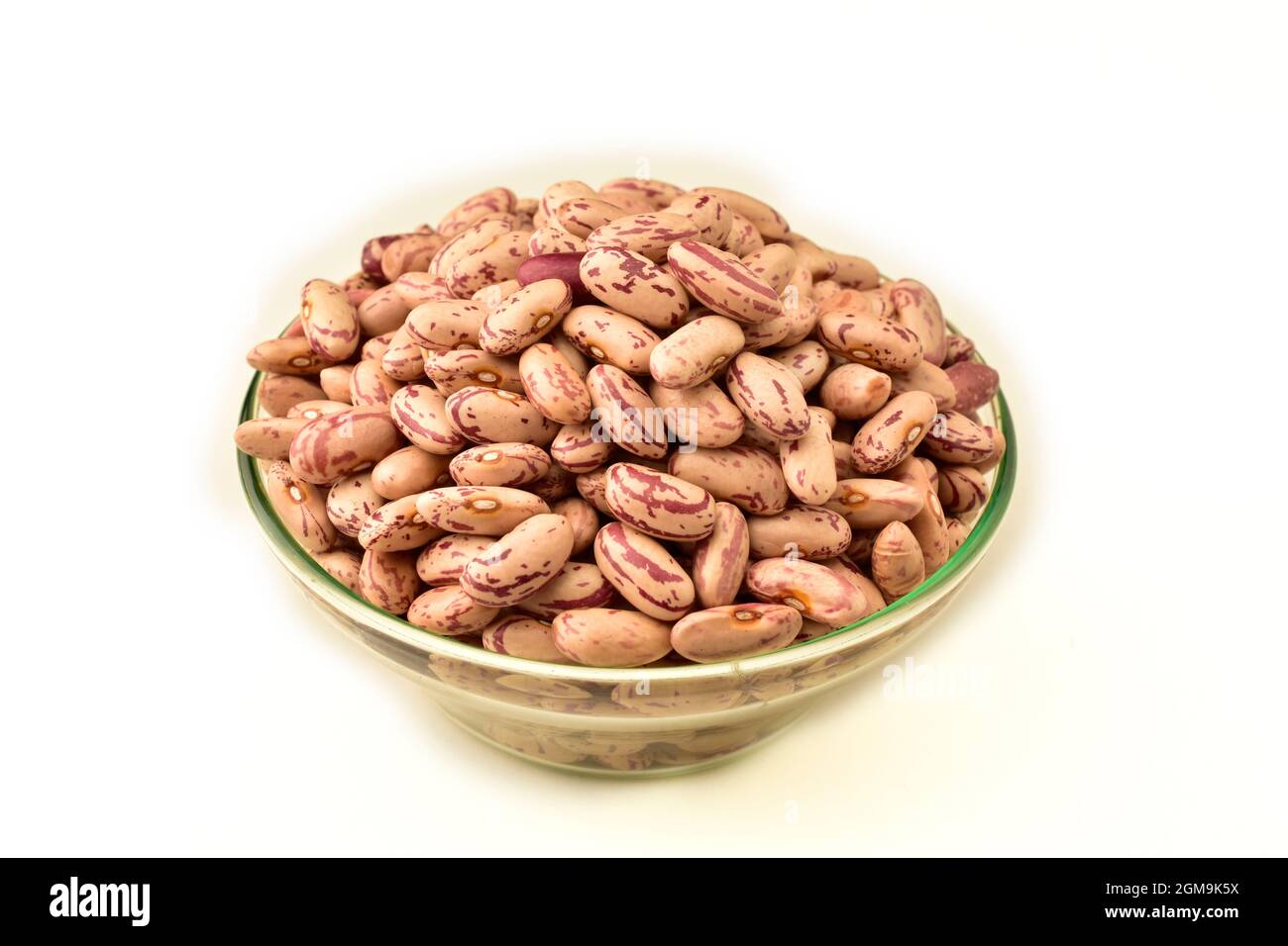 Dry pinto beans in glass bowl isolated on white. Spilled beans Stock