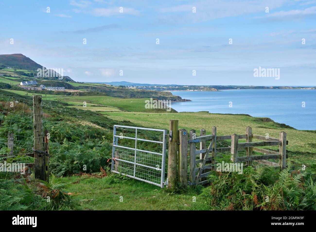 A gateway on the Wales Coast Path near Pistyll leading to open fields with view West along the rugged North Coast of the Lleyn Peninsula Stock Photo